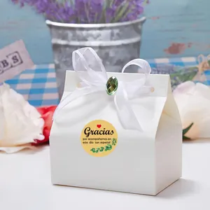 Close-up detail of white gift box featuring green leaf thank you sticker and elegant white ribbon bow