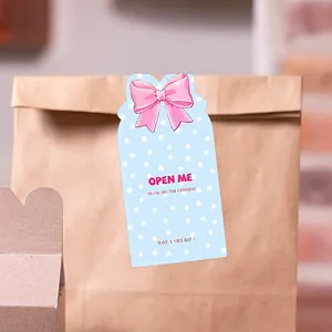 Detaillierte Ansicht eines blauen Siegelaufklebers mit rosa Schleife und 'Open Me' Schriftzug