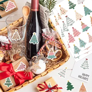 Detailed view of festive Christmas tree stickers applied on gift wrapping and wine bottle.