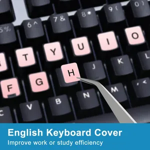 Close-up of pink English keyboard stickers being applied with tweezers on a laptop.