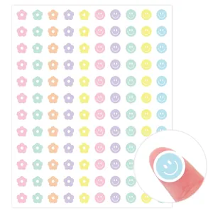 Primer plano de una pegatina de carita sonriente pastel en la yema del dedo mostrando tamaño