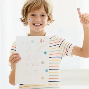 Happy child holding math test with colorful smiley face reward stickers on the paper