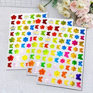 Gedetailleerd overzicht van kleurrijke holografische vlinder- en bloemstickers met glinstering