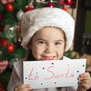 Girl holding an envelope with To Santa text decorated with laser Christmas ball stickers