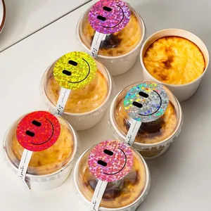 Close-up detail of 5cm colorful holographic smiley face stickers on dessert cup lids.