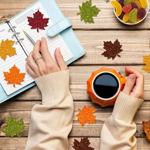 Close-up of glitter autumn maple leaf stickers in 5 colors on a notebook and desk