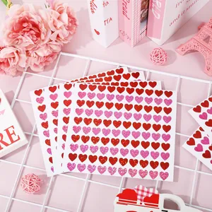 Vista macro de pegatinas de corazones láser rojas y rosas brillantes en hojas blancas