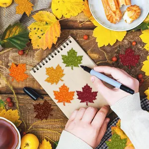 Close-up of glittery autumn maple leaf stickers on a notebook with decorative leaves