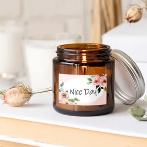 Close-up of a floral label with 'Nice Day' text on an amber jar candle