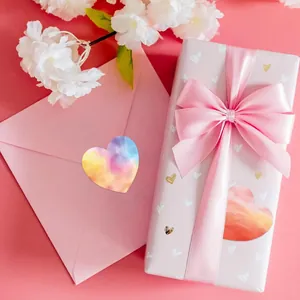 Detalle de pegatinas de corazón de acuarela en una caja de regalo y un sobre rosas