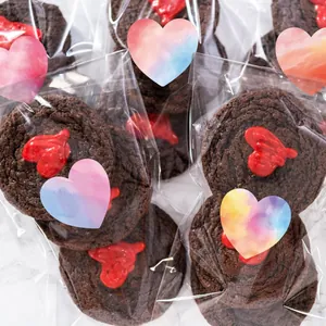 Primer plano de pegatinas de corazón en acuarela sellando bolsas de regalo para galletas caseras.