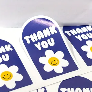 Primer plano de pegatinas azules 'Thank You' con margarita blanca y carita sonriente