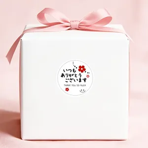 Vista detallada de una pegatina floral de agradecimiento en una caja de regalo blanca