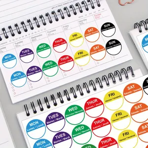 Detailed view of multi-language colorful weekly planner day stickers on a notebook.