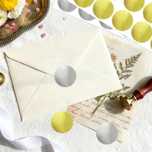 Close-up of 50mm silver gold foil embossed serrated seal sticker on a white envelope.