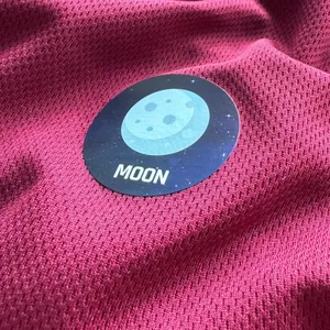 Close-up of a circular moon planet sticker with 'MOON' text on red fabric