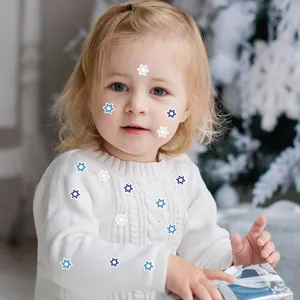 Detalle de pegatinas de la Estrella de David en azul y plata en el jersey blanco de un niño