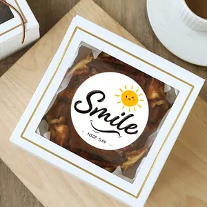 Στρογγυλό λευκό αυτοκόλλητο Smile με κίτρινο ήλιο σε λευκό κουτί αρτοποιίας