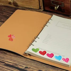 Primer plano de pegatinas decorativas de corazón en una agenda vintage para diario DIY.