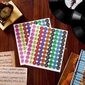 Détail d'autocollants ronds colorés sur le thème de la musique sur un bureau.