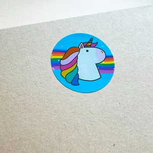 Close-up of a circular sticker featuring a colorful unicorn and rainbow on a blue background