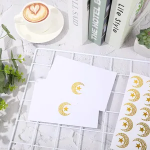 Detailed view of gold foil moon and star seal stickers on white envelopes for invitations