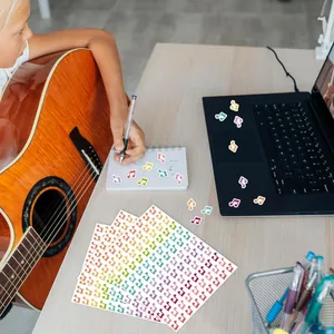 Vibrant musical note stickers applied to a laptop and notebook in a creative desk setting