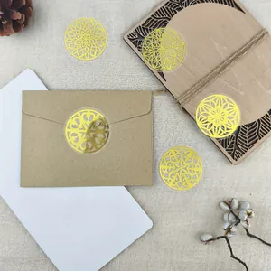 Détail d'autocollants mandalas dorés appliqués sur une enveloppe kraft et carnet.