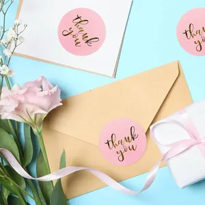Detailed view of pink round stickers with gold foil thank you text on an envelope.