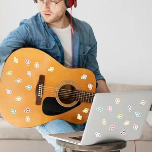 Colorful musical note stickers used as creative DIY decoration on a guitar and laptop