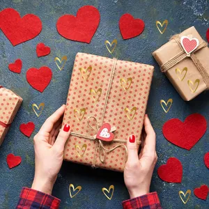 Close-up detail of shiny gold foil heart stickers on a rustic brown gift box wrap