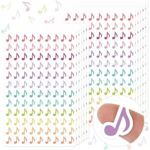 Close-up showing the small scale of a colorful musical note sticker on a fingertip