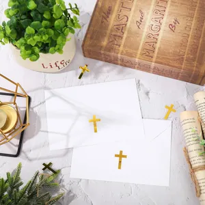 Gold foil cross stickers used as elegant seals on white envelopes for invitations.