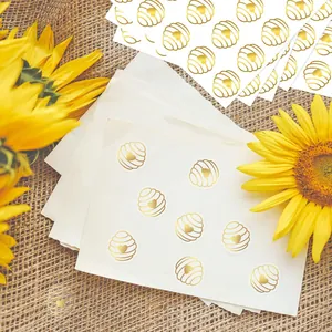 Macro view of gold foil honeycomb heart stickers on a rustic burlap background with sunflowers