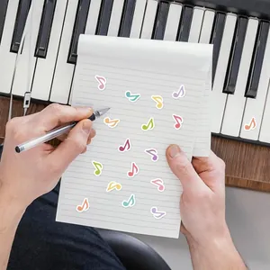 Macro detail of colorful music note stickers on a white notepad next to piano keys