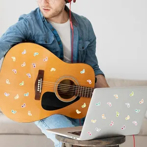Colorful musical note stickers applied on a guitar and laptop for DIY decoration.