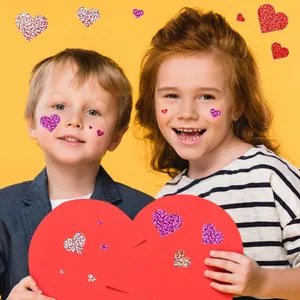 Two smiling children with colorful glitter heart stickers on their faces for decoration.
