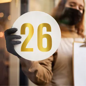 Macro detail of a large golden vinyl number sticker 26 displayed on a white circular plate