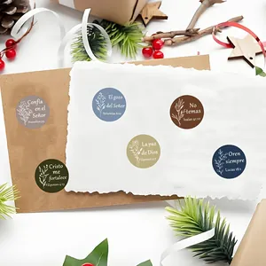 Close-up of round Spanish Bible verse stickers with floral illustrations on white paper background