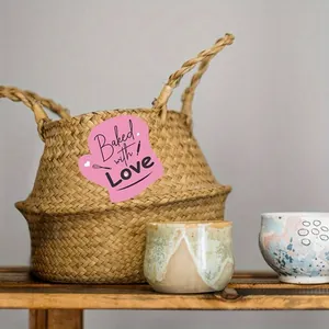 Close-up detail of pink glove-shaped 'Baked with Love' sticker on a woven basket
