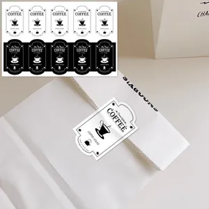 Close-up of black and white coffee-themed rectangular decorative labels on a white paper bag