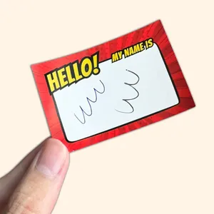 Close-up of a vibrant red comic-style writable name sticker held by a hand for scale