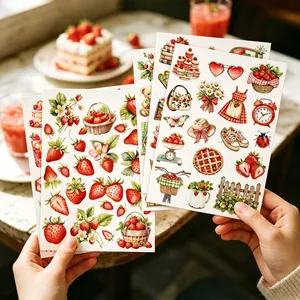 Hand holding multiple sheets of aesthetic strawberry heart stickers for journal DIY