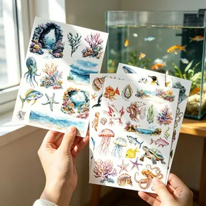 Hands holding four sheets of colorful watercolor ocean themed stickers for journaling