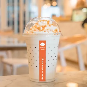 Detail of orange "Thank You" sticker on a polka-dot coffee cup in a cafe setting.