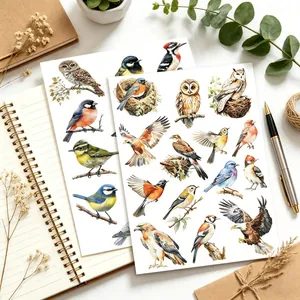 Nahaufnahme von Aquarell-Vogelstickern für DIY-Scrapbooking auf einem Schreibtisch.