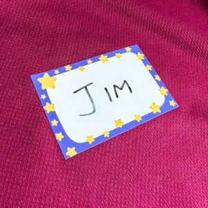 Customizable cartoon star name tag sticker featuring handwritten Jim on burgundy background