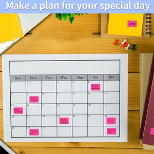 Primo piano di etichette adesive rosa per la pianificazione su un calendario da tavolo