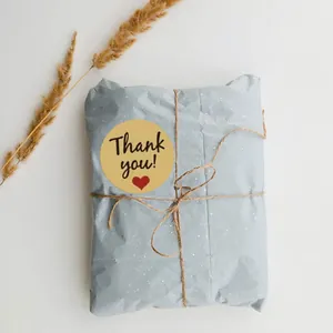 Κοντινό πλάνο αυτοκόλλητου Thank You από χαρτί κραφτ σε μπλε συσκευασία δώρου.