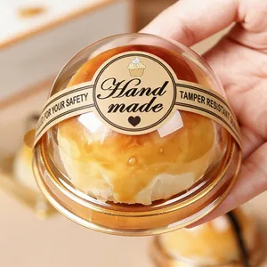 Primo piano di un adesivo marrone "Hand made" su un contenitore per dolci trasparente.